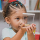 Child holding a clear container with caterpillars inside, looking at it with curiosity.