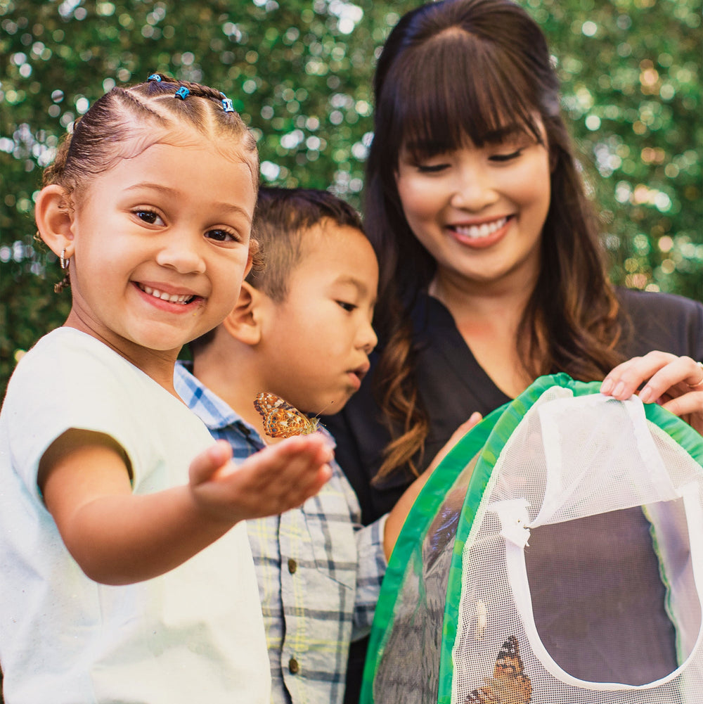 Woman and two children with a butterfly in a net, outdoors.