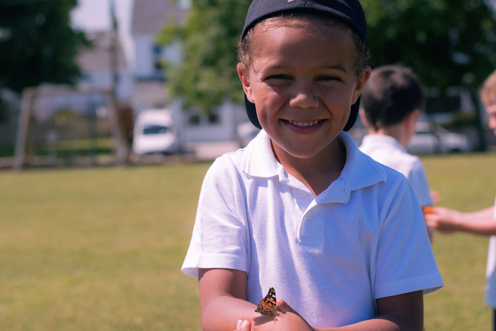 Child holding a butterfly outdoors on a sunny day
